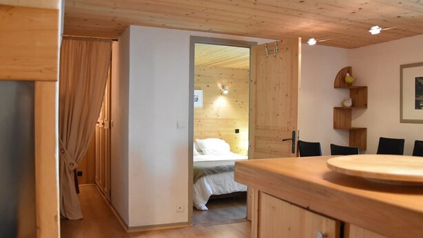 Un interno in legno con un letto, un tavolo da pranzo e un angolo cottura.