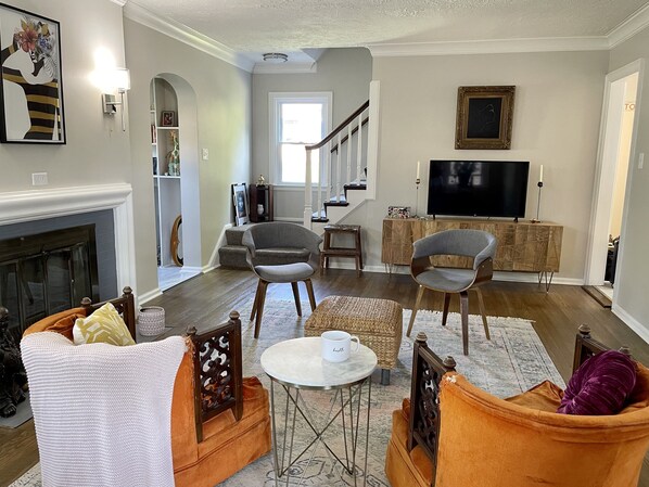 Un salon avec une cheminée, deux fauteuils, une table basse et un téléviseur.