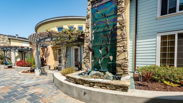 A courtyard with stone pathways, a decorative metal gate, and a small water feature. - Luxe Designer Condo w/BBQ, Gourmet Kitchen & ½ Block to the Beach in Avila! (Avila Beach, CA)