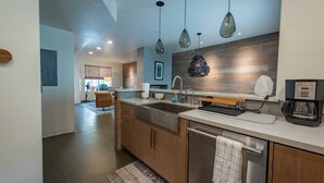 A modern kitchen with a large island, stainless steel appliances, pendant lighting, and a view to the living area. - Luxe Designer Condo w/BBQ, Gourmet Kitchen & ½ Block to the Beach in Avila! (Avila Beach, CA)