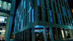 Un hotel modern amb un senyal prominent de 'HOTEL ONE', grans finestres i una entrada ben il·luminada.