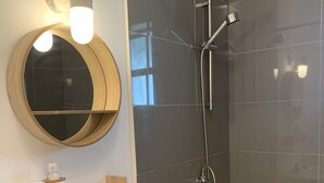 A bathroom with a round mirror, a white sink, and a shower with a glass door. - Modern & Private Sun Valley getaway for two (Sun Valley)