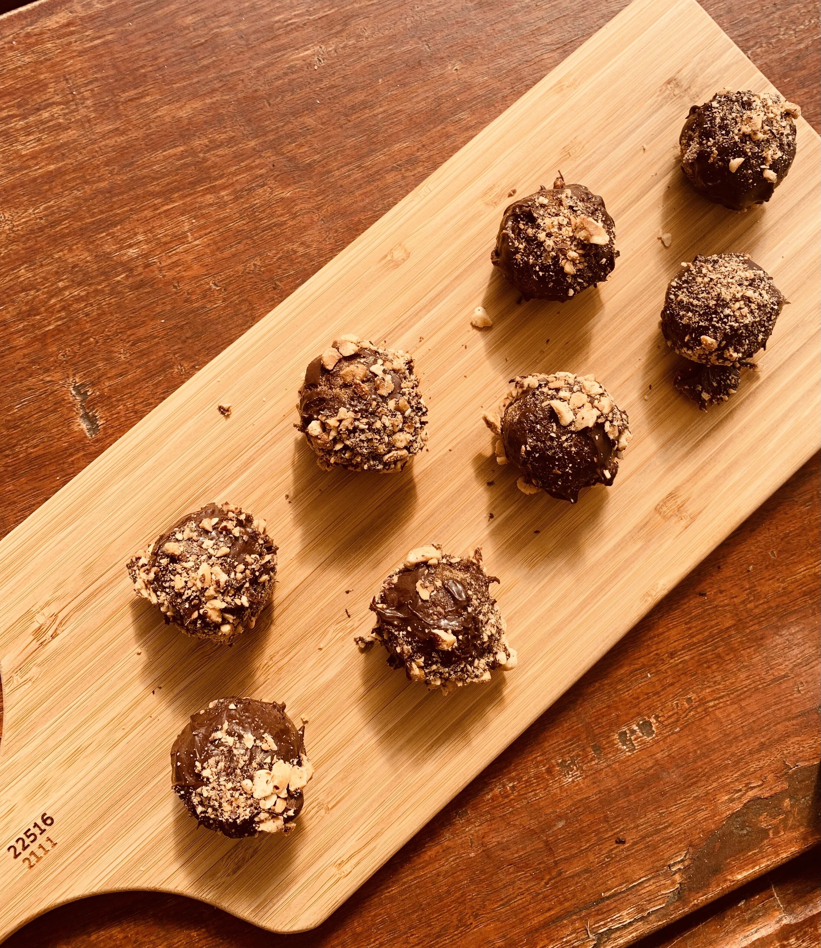Una tabla de madera con varias golosinas bañadas en chocolate.