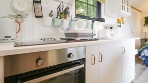 A modern kitchen with white cabinets, a Breville coffee maker, a toaster, and a window with a view of greenery. - High Rigg Shepherd's Sunset (Brampton)
