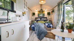 A compact room with a bed, a dining table, and a kitchen area. - High Rigg Shepherd's Sunset (Brampton)