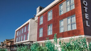 Een hotel met een moderne gevel, grote ramen en een zichtbaar balkon.