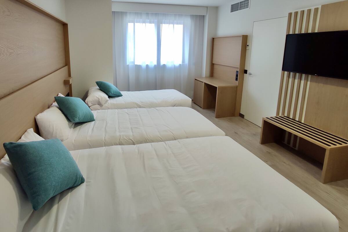 A hotel room with two beds, a TV, and a desk.
