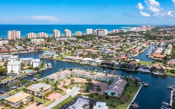 An aerial view of a coastal city with a marina, residential buildings, and a beachfront. - Waterfront 2BR/2BA condo with heated pool, WiFi, and marina access. (Marco Island)