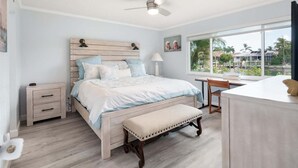 Une chambre à coucher avec un lit, des tables de chevet, un bureau et une fenêtre donnant sur un beau paysage.