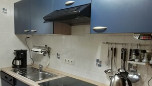Een keuken met een vaatwasser, fornuis en waterkoker. Er zijn kastjes en een aanrecht.