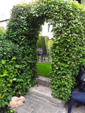 A garden entrance with a stone pathway leading to a seating area.