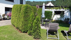 A well-maintained garden with a neatly trimmed hedge, outdoor furniture, and a patio area. - Vacation apartment Hunz - Apartment 2 (Schutz)
