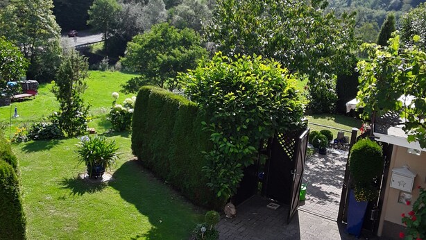 A garden pathway leading to a covered area with a view of a forested hill. - Vacation apartment Hunz - Apartment 2 (Schutz)