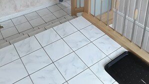 A kitchen with white marble tiles, a wooden railing, and a black sink. - Vacation apartment Hunz - Apartment 2 (Schutz)