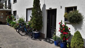 A building with multiple windows and doors, potted plants, and bicycles parked outside. - Vacation apartment Hunz - Apartment 2 (Schutz)