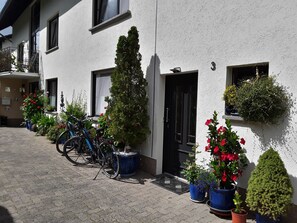 Ein Gebäude mit mehreren Fenstern und Türen, Blumentöpfen und Fahrrädern vor der Tür.