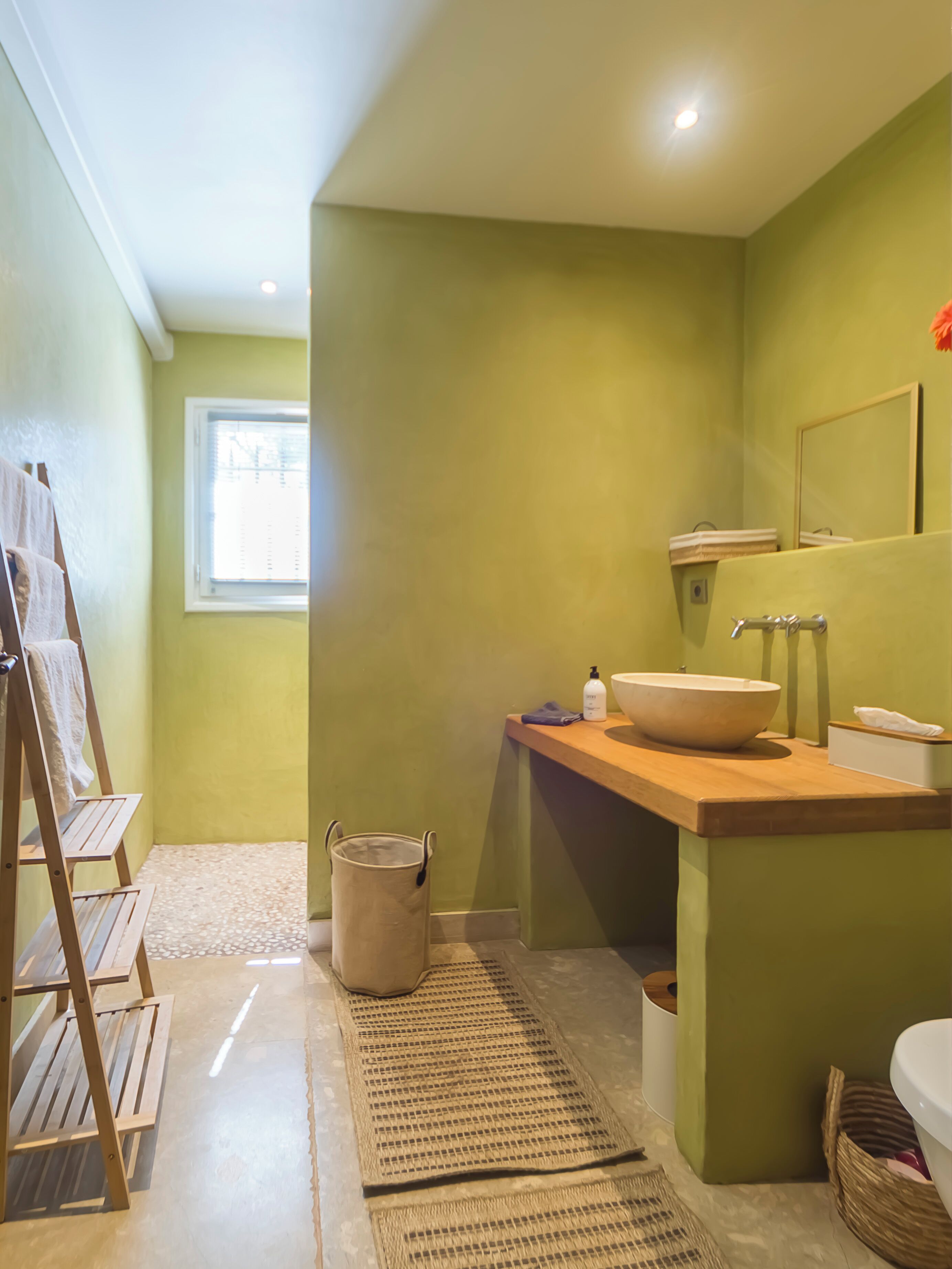 Une salle de bain avec un meuble-lavabo en bois, un grand miroir et une fenêtre.