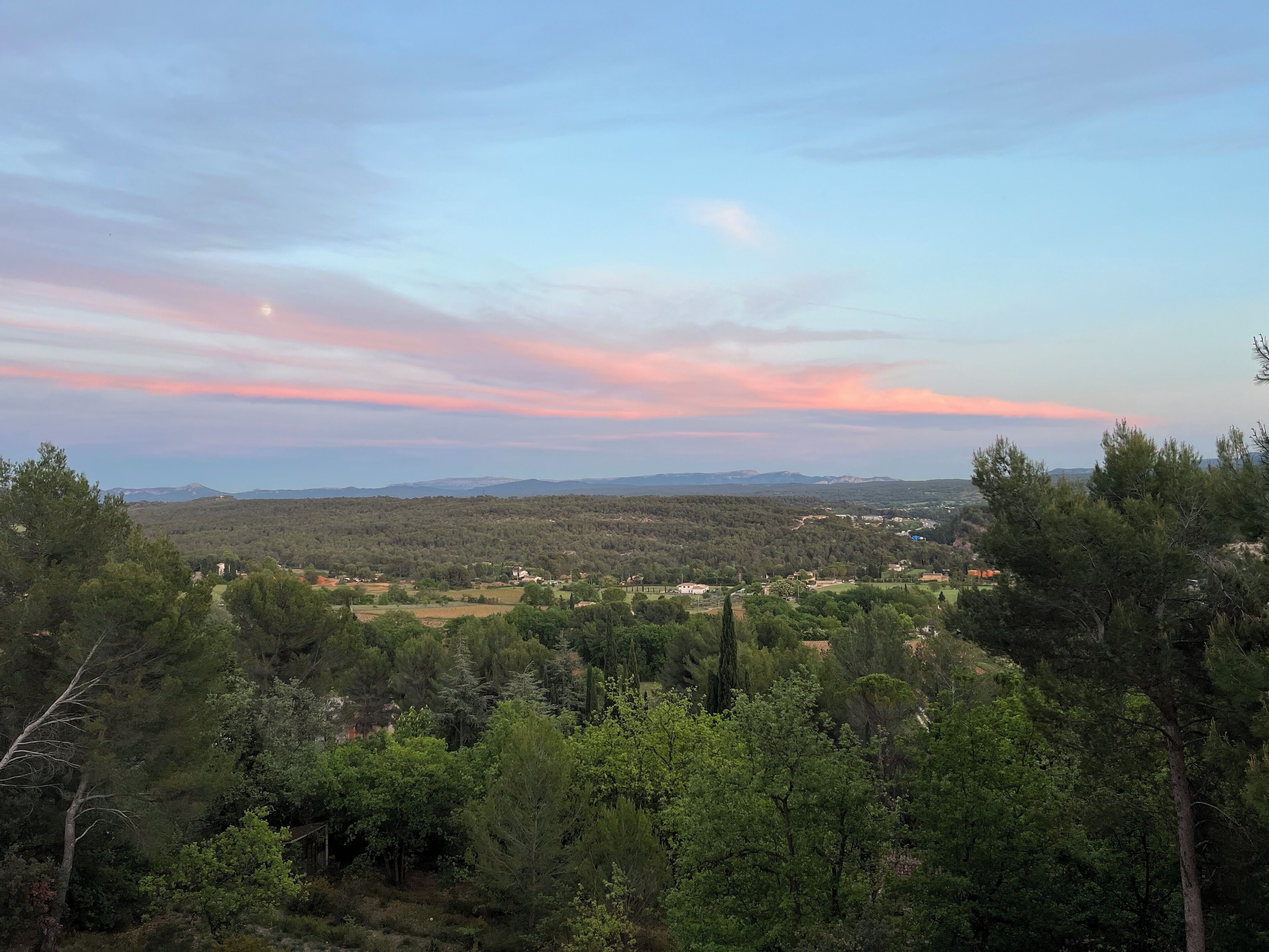 A landscape view with a clear sky, trees, and distant hills.