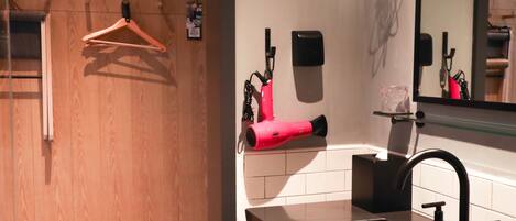 A bathroom with a wooden panel wall, a black sink, a mirror, and a red hairdryer.