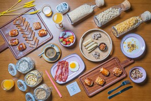 A breakfast spread with various foods and drinks on a wooden table. - Moxy Shenzhen North Station (Shenzhen)