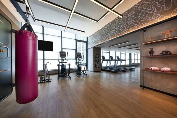 A gym with exercise equipment, a punching bag, treadmills, and a wall with a motivational quote. - Moxy Shenzhen North Station (Shenzhen)