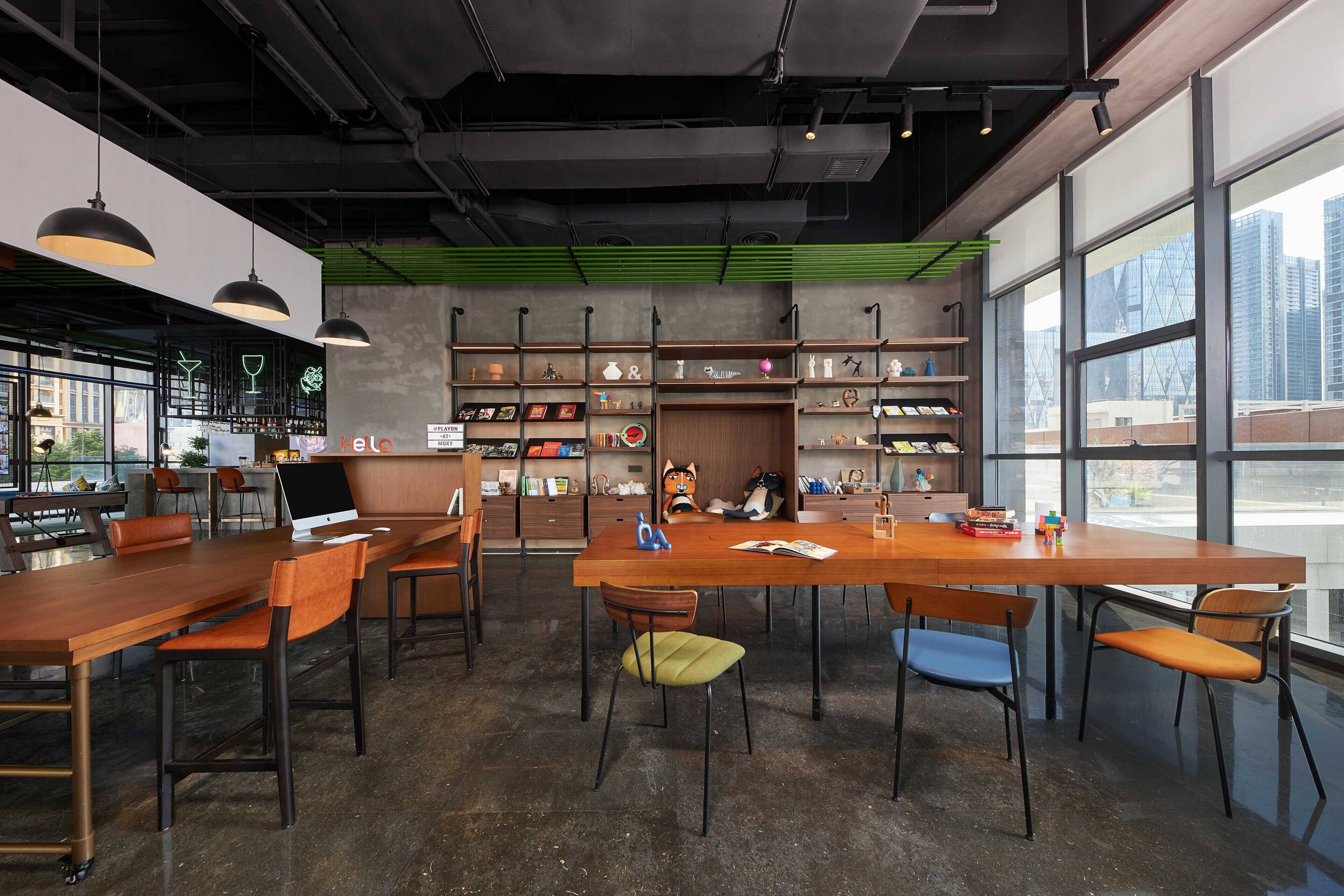 Un café moderno con mesas y sillas de madera, una zona de bar y grandes ventanales con vistas a la ciudad.