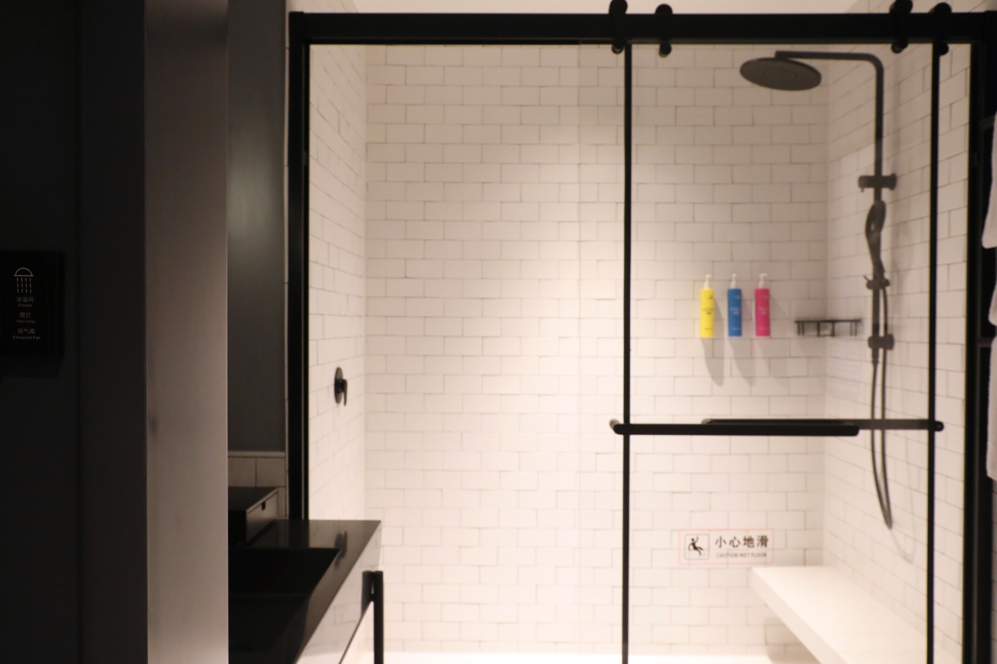 A modern bathroom with white subway tiles, a glass-enclosed shower, and a black towel rack.