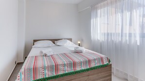 A neatly made bed with white linens, a patterned blanket, and a wooden headboard. - SUEDE 4 - balcon & clim, à 100 m plage - By Rivier (Niza)