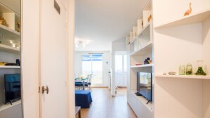 A narrow hallway with a dining area at the end, featuring a table and chairs. Shelves line the walls, holding various items. - PASSY AZUR AP4242 - Vue mer à 10 min de la plage (Niza)