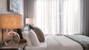 A hotel room with a bed, a nightstand with a lamp, and sheer curtains. - Dahlia Daylesford - Free WIFI walking distance to Botanic Gardens with spa bath! (Daylesford)