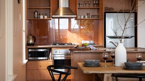 A modern kitchen with wooden cabinets, stainless steel appliances, and a central island with seating. - Dahlia Daylesford - Free WIFI walking distance to Botanic Gardens with spa bath! (Daylesford)