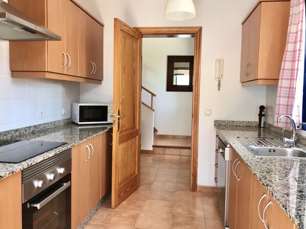 Una cocina con armarios de madera, microondas, estufa y fregadero.