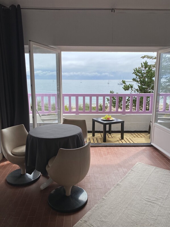 A balcony with a view of the sea, a table with a plate of fruit, and a chair. - Studio in a magnificent Villa, exceptional location, private beach access. (AUDIERNE)