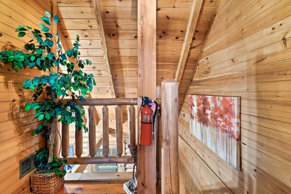 A wooden cabin interior with a wooden railing, a fire extinguisher, and a wall-mounted basket. - Discount!Hot Tub, Pool & Fishing, Arcade, WiFi, Fireplace in a beautiful resort. (Sevierville)