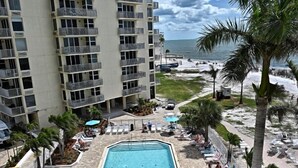 A hotel with a swimming pool surrounded by lounge chairs and palm trees. - Welcome To Pleasant Paradise (Fort Myers Beach)