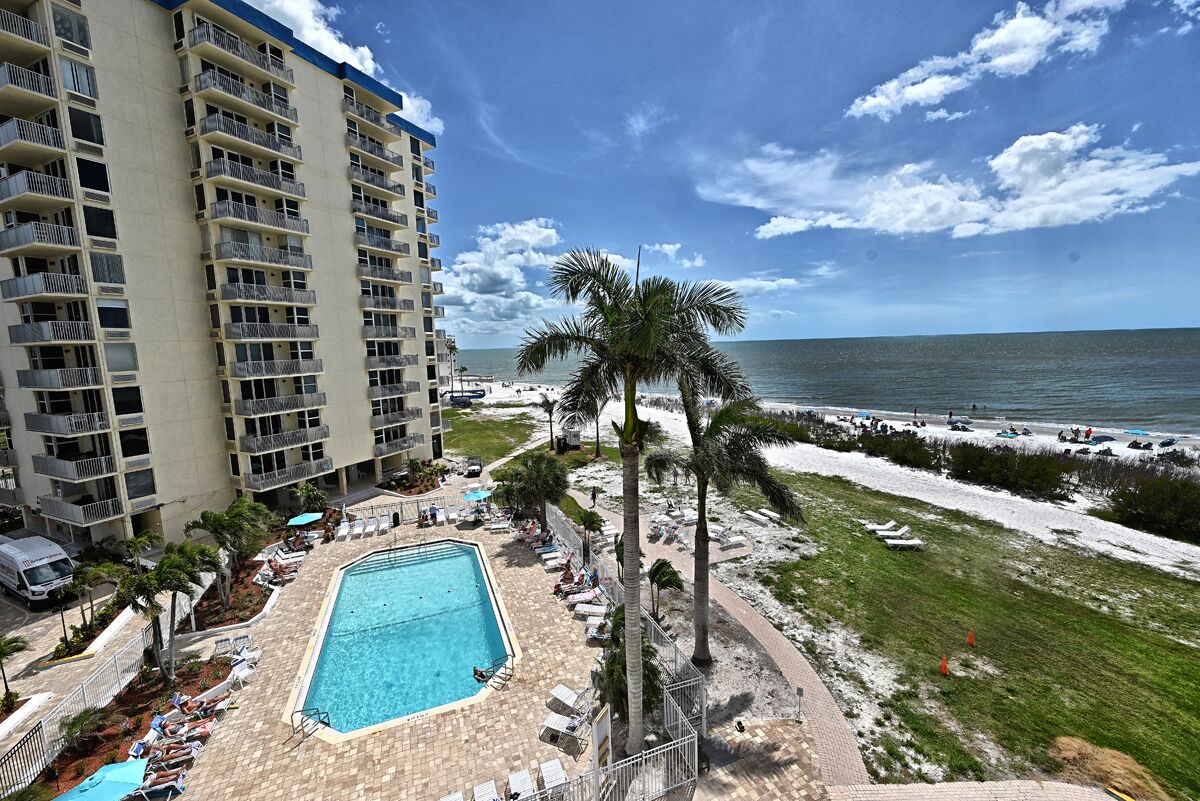 A hotel with a pool, beach view, and a tall building in the background.
