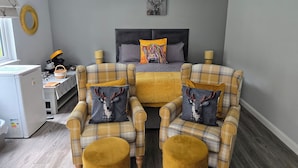 A modern bedroom with a bed, two armchairs, a small table, and a desk. - Beautiful Studio Chalet in the Highlands (Inverness)