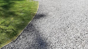 A gravel driveway leading to a wooden cabin with a metal roof, surrounded by a grassy area and potted plants. - Beautiful Studio Chalet in the Highlands (Inverness)