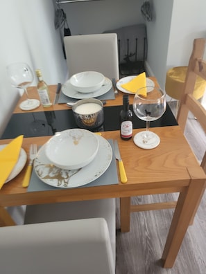 Enjoy a meal at this elegant dining table, set with fine tableware and a bottle of wine.