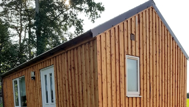A wooden building with a door and windows, surrounded by a gravel path and small plants. - Beautiful Studio Chalet in the Highlands (Inverness)