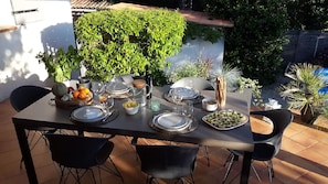 Enjoy dining al fresco in this outdoor space with a table set for four, surrounded by lush greenery.