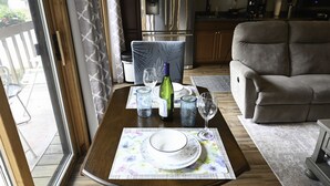 A dining area with a table set for two, a sofa, and a kitchen in the background. - Shanty Creek/ Schuss Close to lakes boat parking. golf course Sleeps 2 adults. (Mancelona)