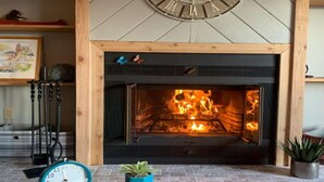 A fireplace with a clock above it, a small table with a plant, and a framed picture on a shelf. - Shanty Creek/ Schuss Close to lakes boat parking. golf course Sleeps 2 adults. (Mancelona)