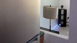 Ett kök med ett inbyggt kylskåp, ett inramat citat på väggen, en tv som hänger ovanför en svart hylla och en golvlampa.