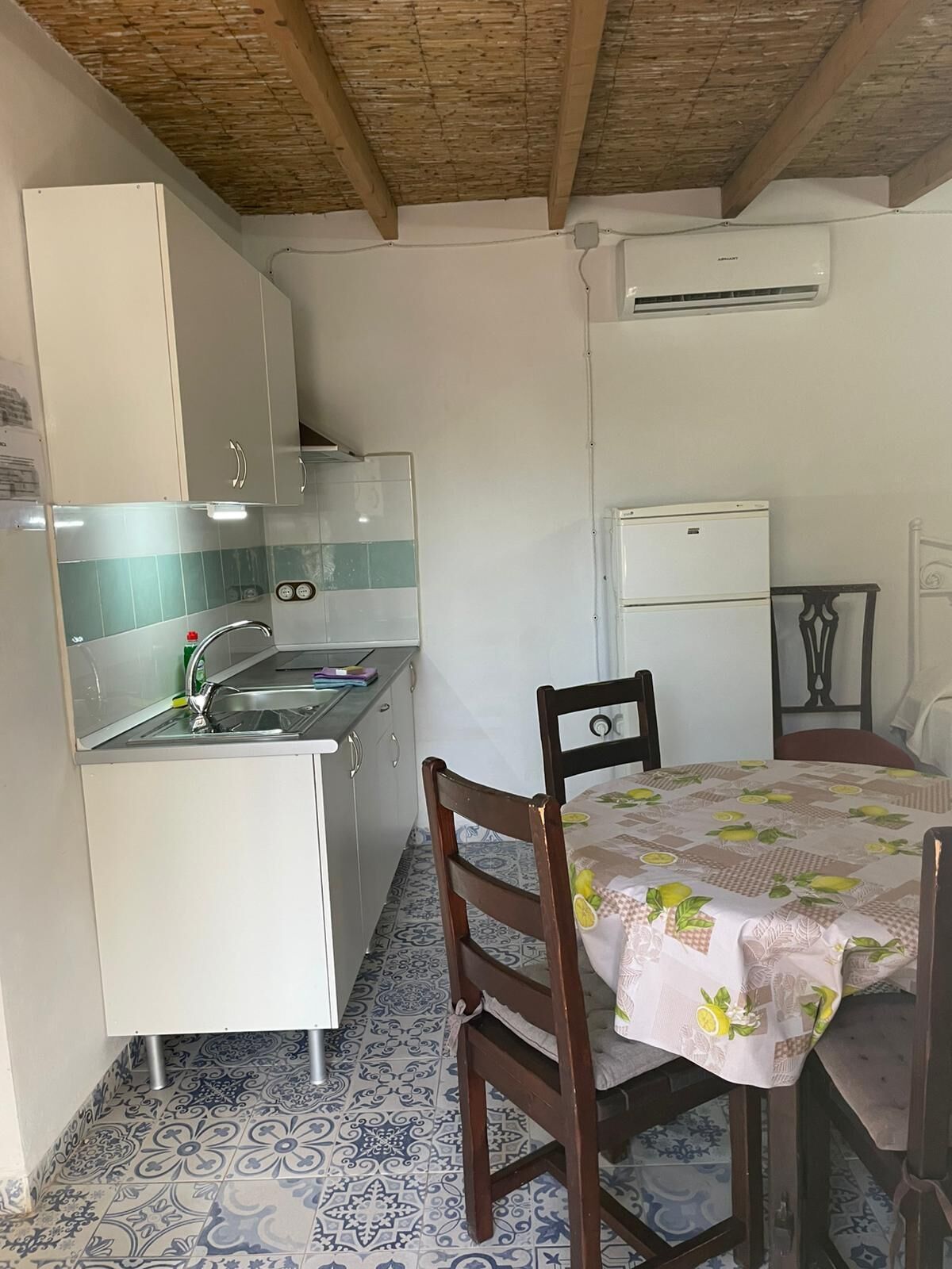 Cocina compacta con lavabo, estufa y zona de comedor con mesa y sillas.