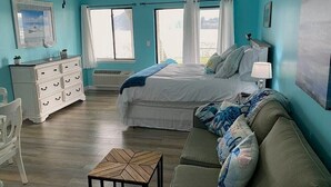 Ein Schlafzimmer mit Bett, Kommode, Stuhl, Tisch und Fenster.