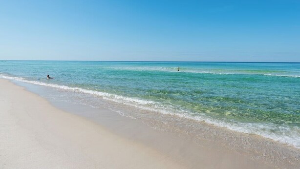Ein Strand mit klarem türkisblauem Wasser und einem Sandufer.