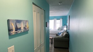 Ein Flur mit einer Tür zu einem Wohnbereich, der eine Couch und ein Segelbootgemälde an der Wand zeigt.