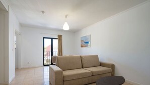 Un salón con un sofá color beige, una mesita redonda y un cuadro en la pared.