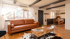 Uma sala de estar com sofá de couro, mesa de centro de madeira e tapete de couro.